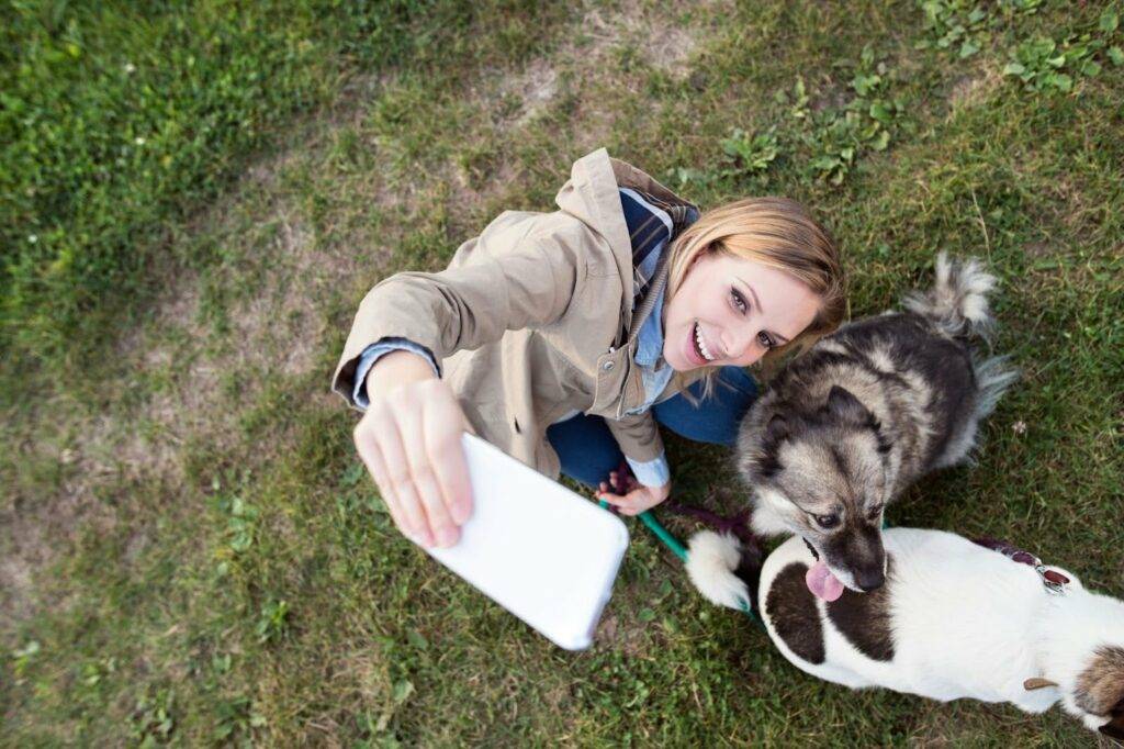 A woman smiling while taking a selfie with her dogs, knowing she doesn’t have to worry about muddy paws because she has booked a professional carpet cleaning with Amazing Results.