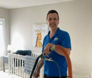 Employee of Amazing Results doing a professional steam cleaning on a carpet in a baby's nursery.