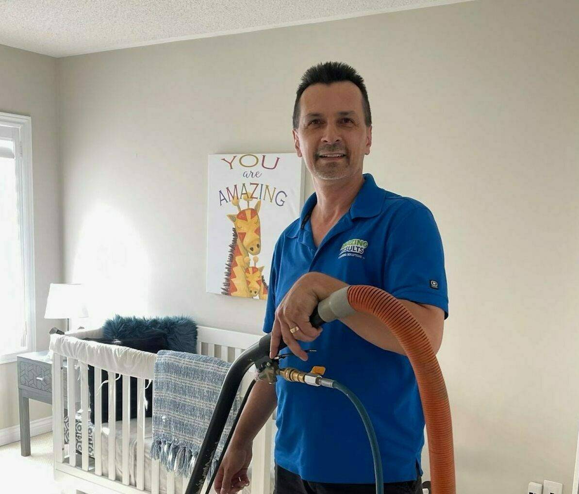 Employee of Amazing Results doing a professional steam cleaning on a carpet in a baby's nursery.