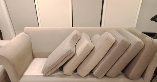 Beige sofa with all seat and back cushions stacked sideways to see hidden dirt in the upholstery.